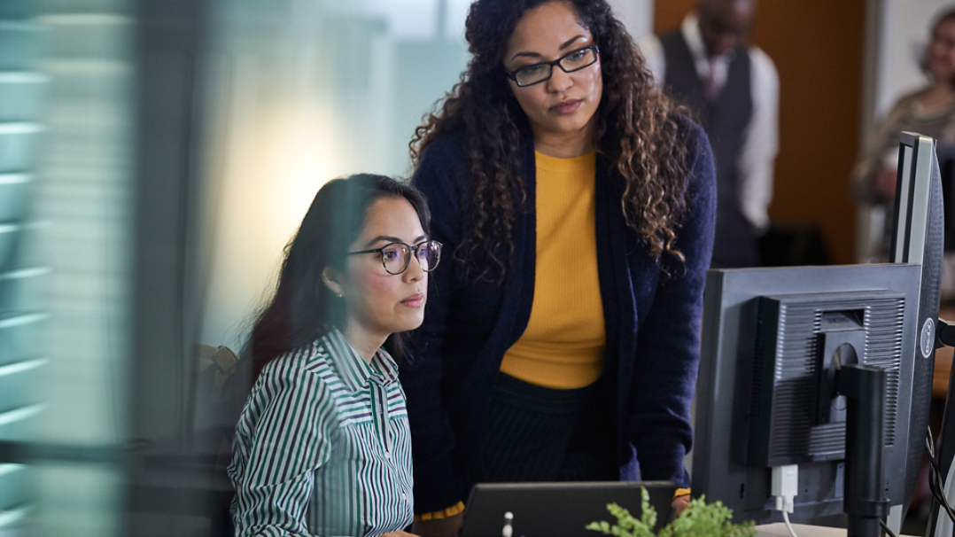 Two women looking at a workstation screen.