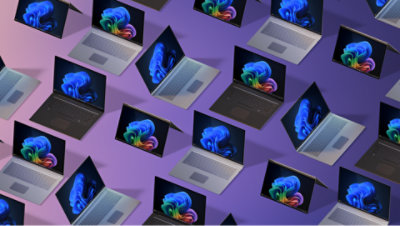 Plusieurs ordinateurs portables ouverts en noir, argent et gris, disposés en diagonale sur un arrière-plan dégradé violet, tous affichant un papier peint bleu fleuri.