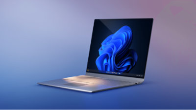 Ordinateur portable métallique ouvert avec un papier peint bleu fleuri, placé sur un arrière-plan dégradé de bleu à violet.