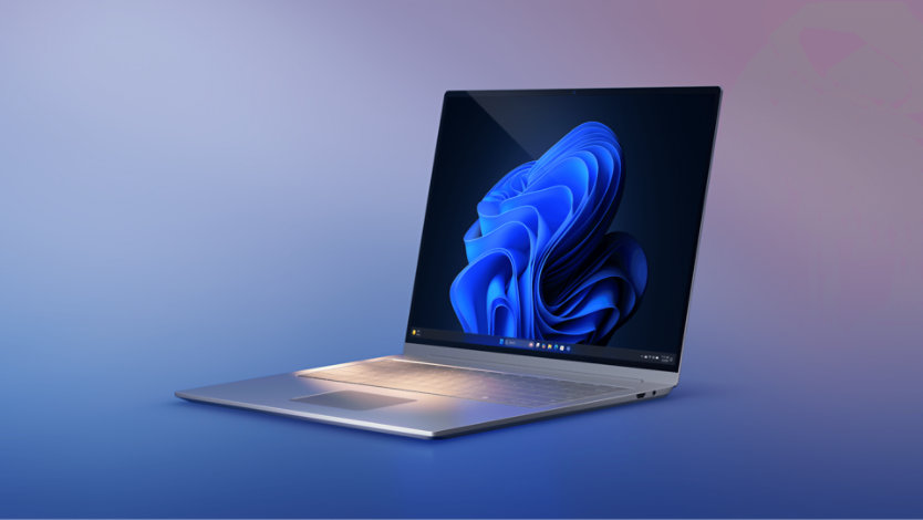 Open metallic laptop with a blue bloom wallpaper, placed on a blue-to-purple gradient background.