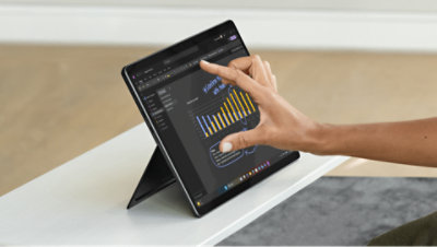 A person using a tablet displaying a bar graph with yellow and blue bars and annotations