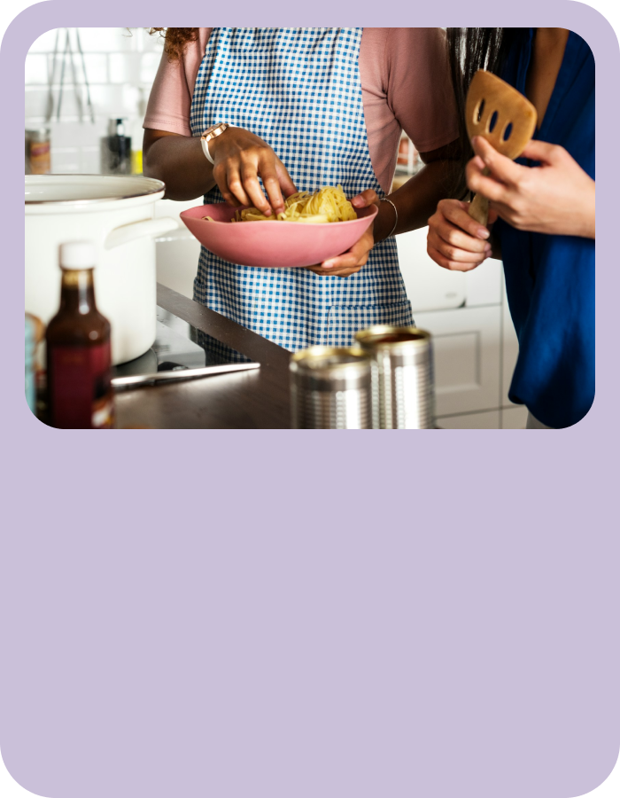 Two people standing in a bright kitchen, chopping and preparing food together on a countertop.