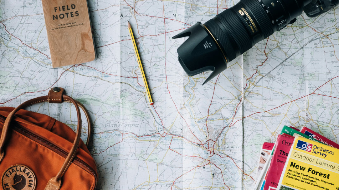 Image of a camera, travel book, trael bag, and map