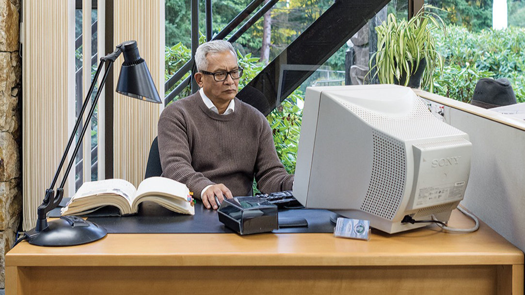 Image of a male office worker using an older-looking desktop computer