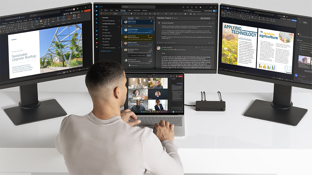 Image of a man collaborating on a Surface Laptop Copilot+ PC on a Teams call with 3 monitors