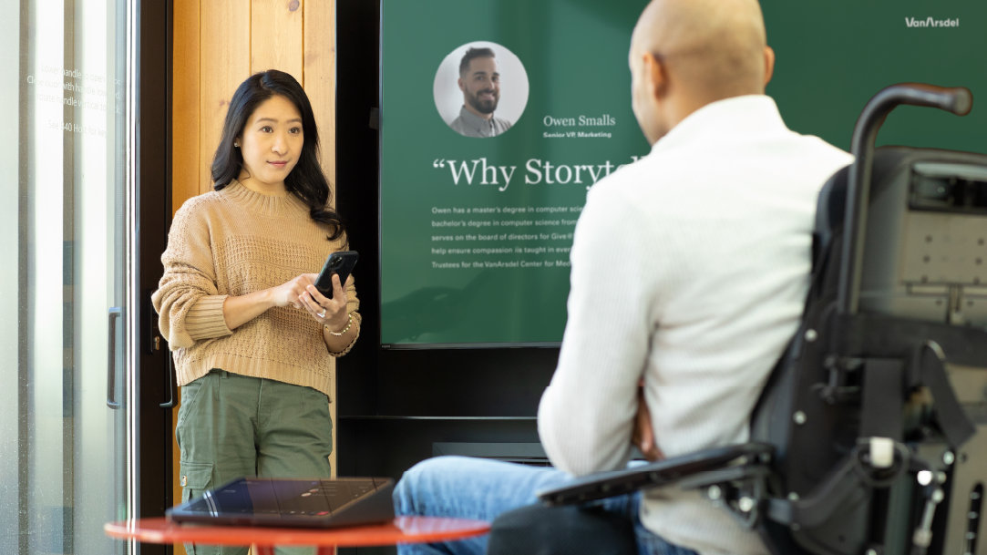 Image of a woman and a man in a living room watching a big screen TV while also using a Surface Pro to check email