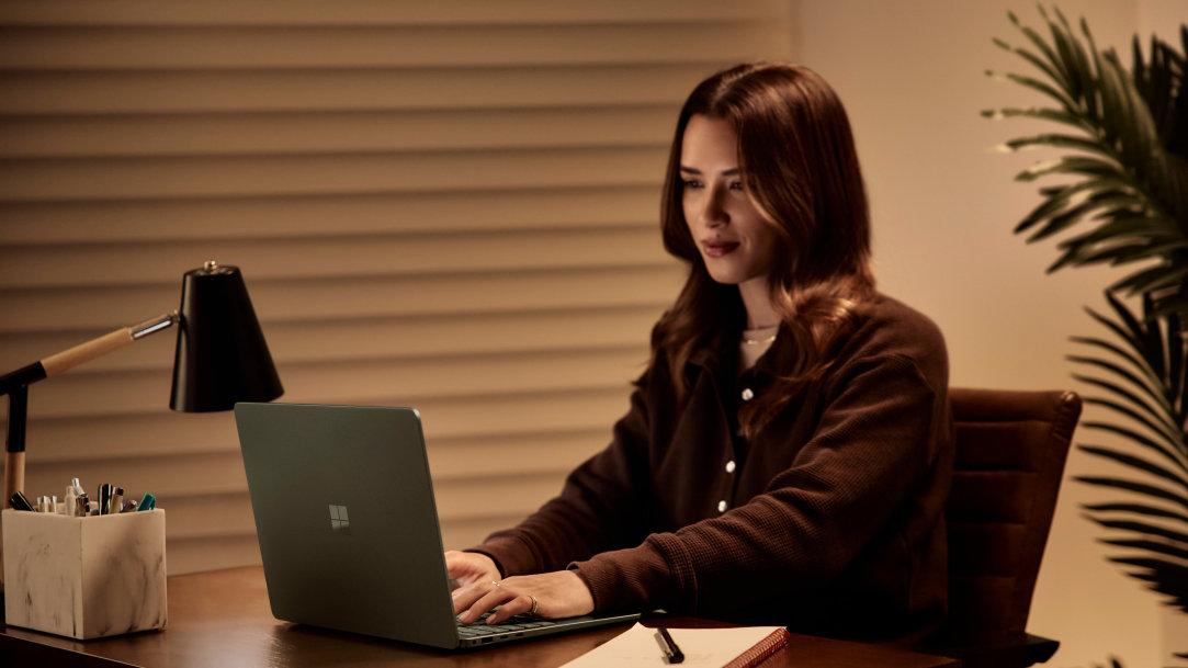 Image of a woman sitting at a desk using a Surface Laptop