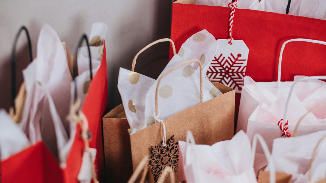 Image of brown and red gift bags with white tissue paper and red snowflake decorations