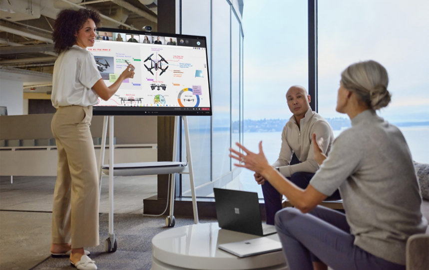 Fysiek aanwezige collega's hebben interactie met een PowerPoint-presentatie in Teams terwijl externe collega's toekijken
