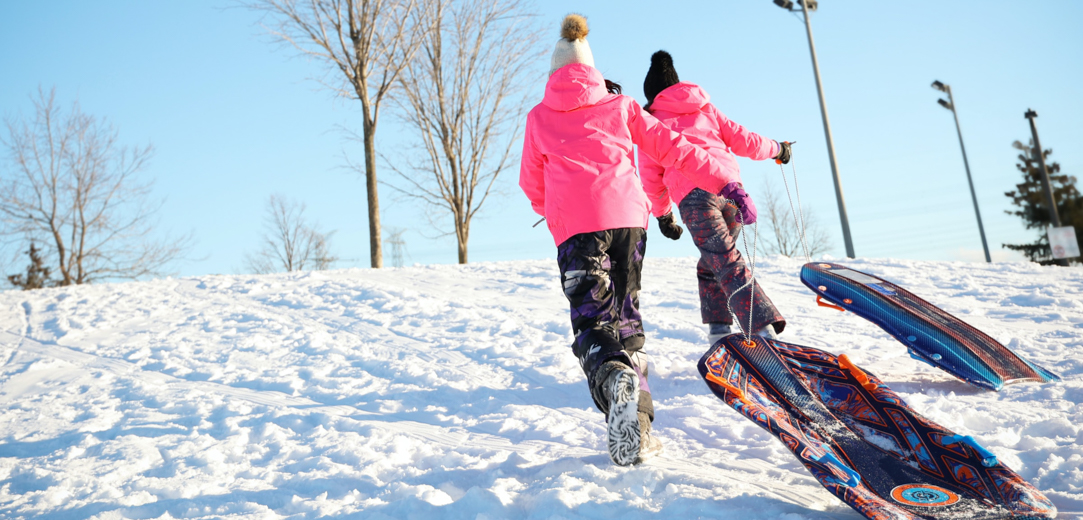 Kids pulling sleds up a snow-covered hill