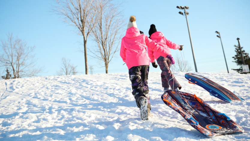 Kids pulling sleds up a snow-covered hill
