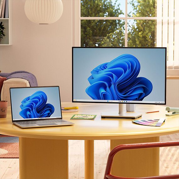 Notebook a stolní počítače s květem Windows na obrazovce položené na stole