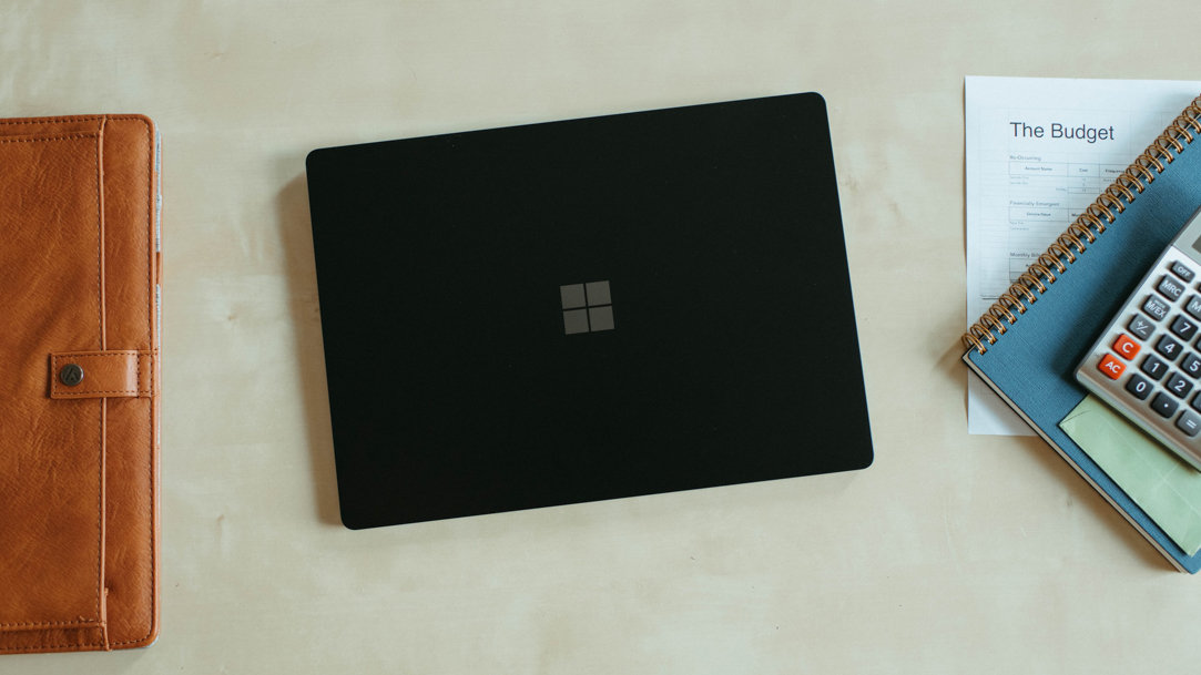 Laptop sitting on a surface next to a notebook and a calculator