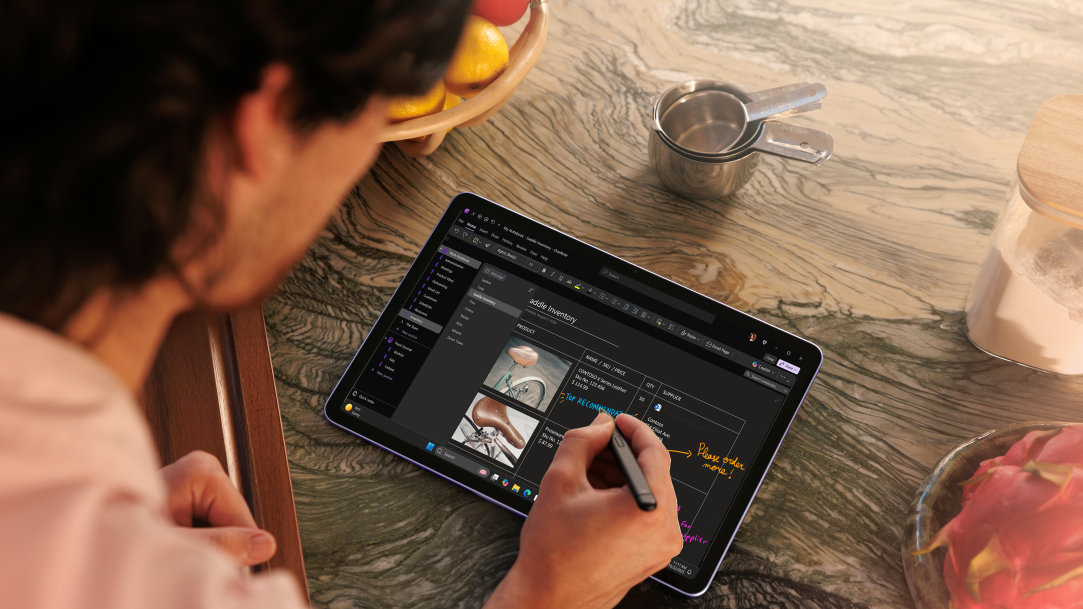 Looking over the shoulder of an adult male using a Surface Pro and handwriting on screen with Surface Slim Pen