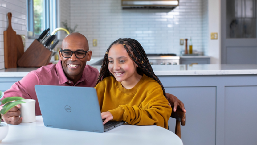 Man and child at kitchen table sharing a Surface laptop