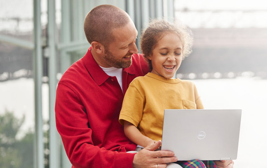 Een man en een klein meisje die lachend naar een laptop kijken