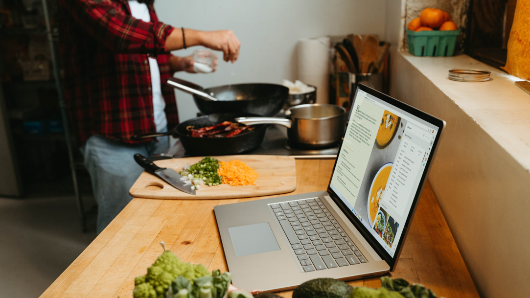 Man cooks dinner while reading a recipe in his Microsoft Edge browser