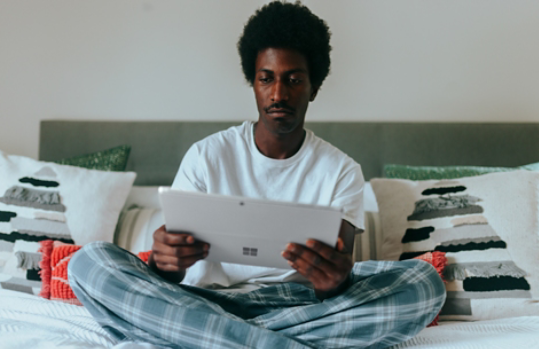 Man in bed reading on a Surface device