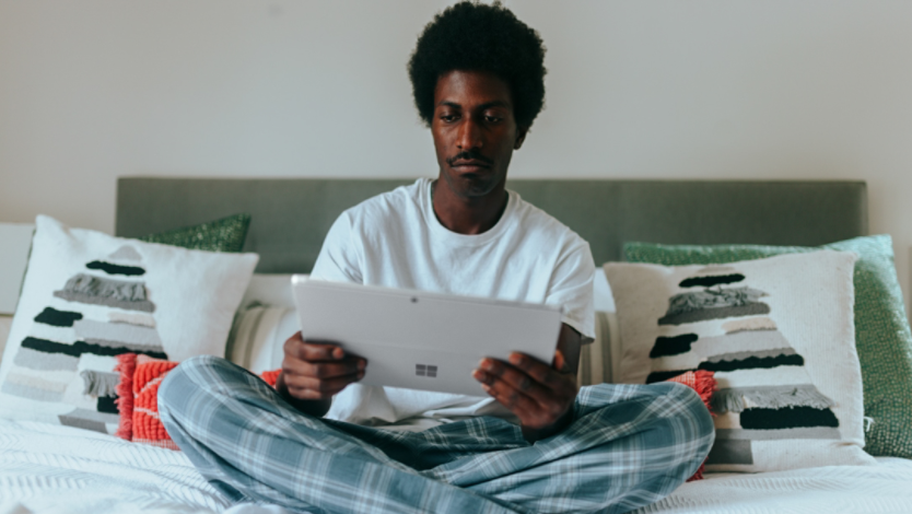 Man in bed reading on a Surface device
