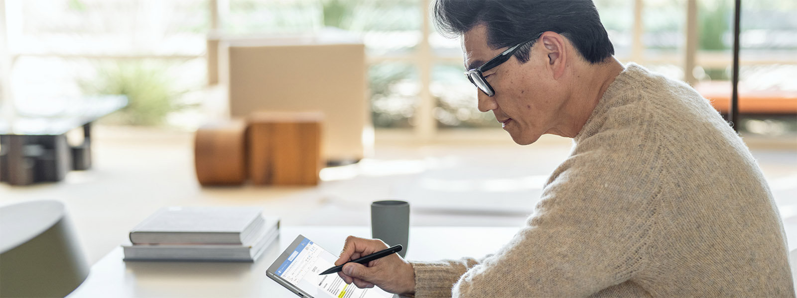 Man sitting at table using a Surface pen on his Surface device