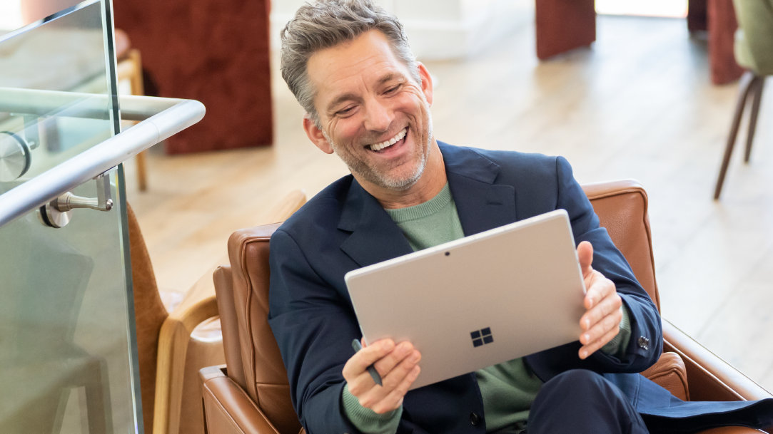 Man smiling and using a Surface device in an open workspace