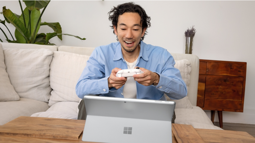 Man using a wireless controller to play games on a 2-in-1