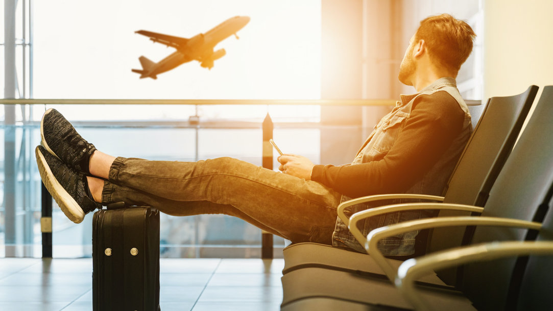 Man waiting at airport with his feet resting on his suitcase