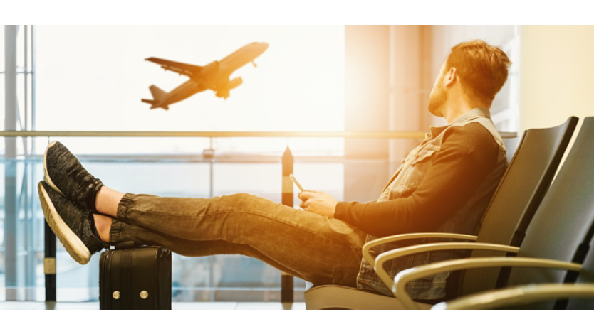Man waiting at airport with his feet resting on his suitcase