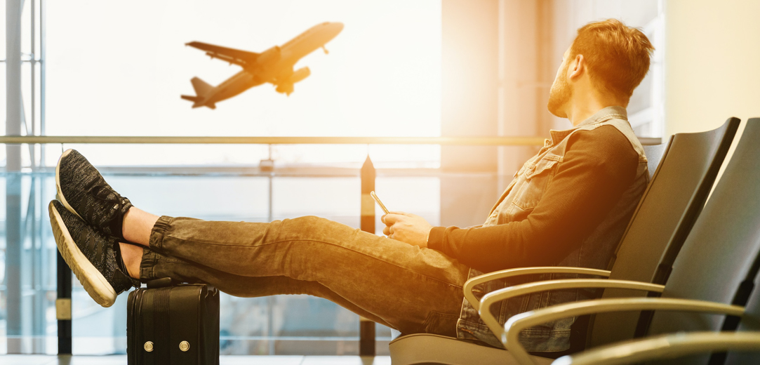 Man waiting at airport with his feet resting on his suitcase