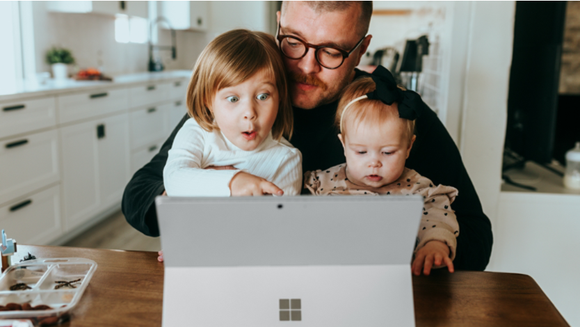 Man with two young children looking at Microsoft Edge on a Surface device