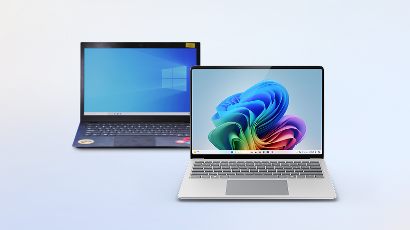 Two open Surface laptops, one with the Windows logo on the screen, and the other with the Windows colorful bloom