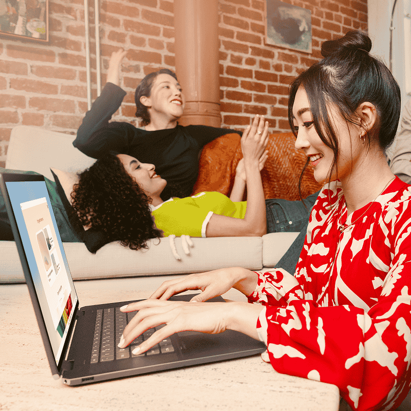 ノート PC でタイピングする女性と、その後ろのソファに横たわっている 2 人の人物がいる側面図