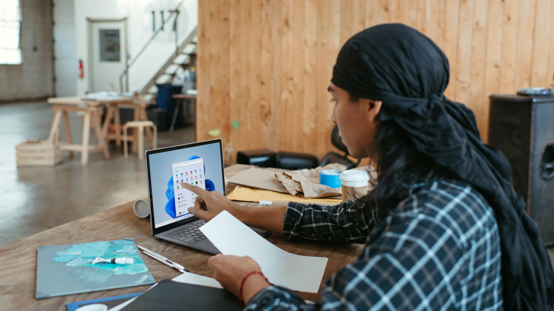 Person at table using touchscreen to open app in Start menu