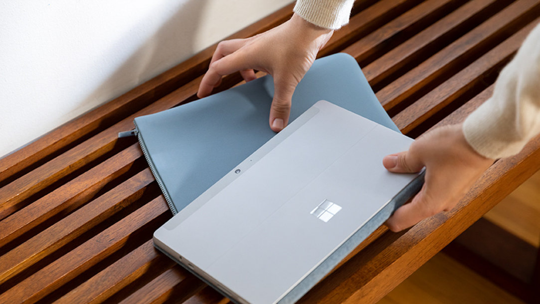 Person holding a Surface laptop with a cover beneath it