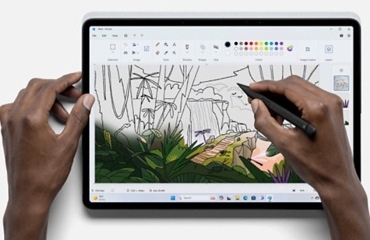 Una persona sostiene un lápiz y usa la app Paint para crear una imagen.