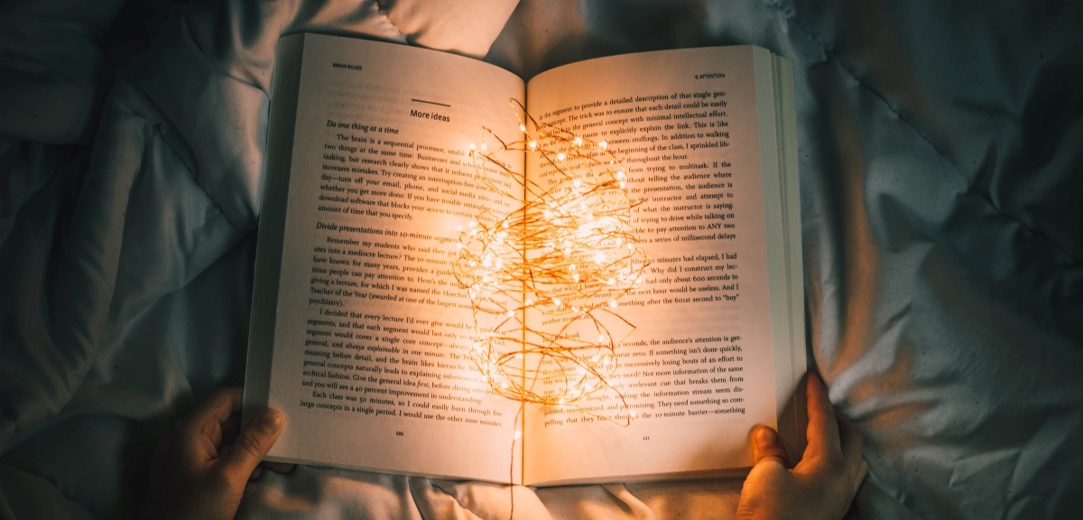 Person holding an open book with lights sitting on top