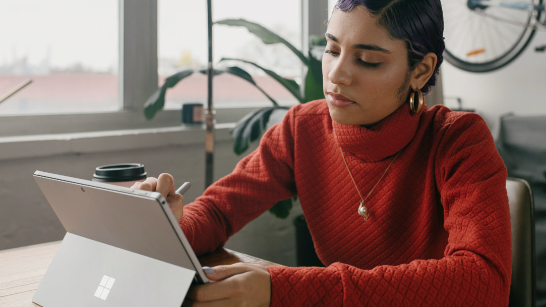 Person in a red sweater uses a Surface pen