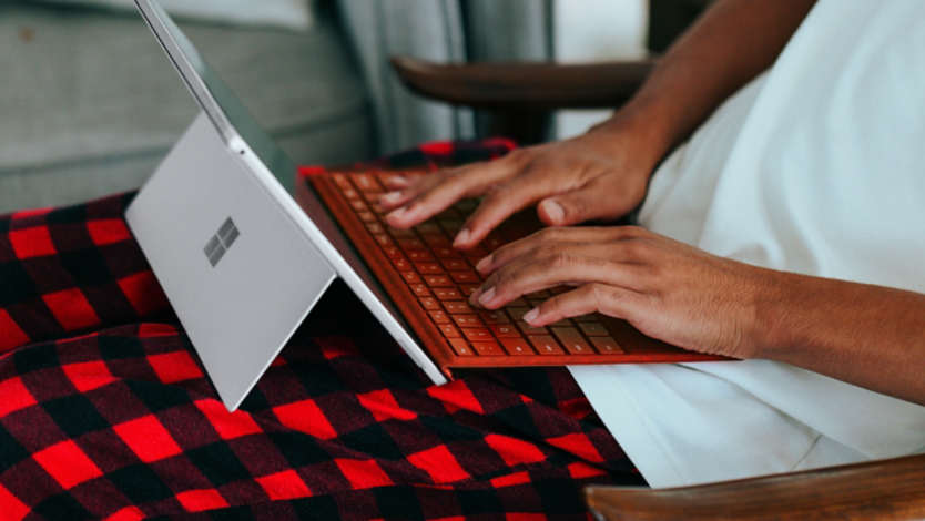 Person in checkered pajamas on their Surface 2-in-1 laptop at home