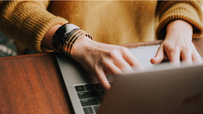 Person in yellow sweater using laptop computer