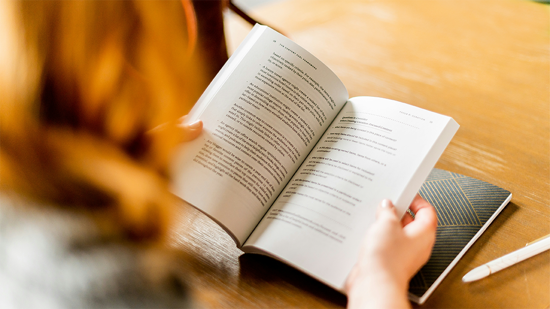 Person preparing for book discussions reading book at a brown wooden table 