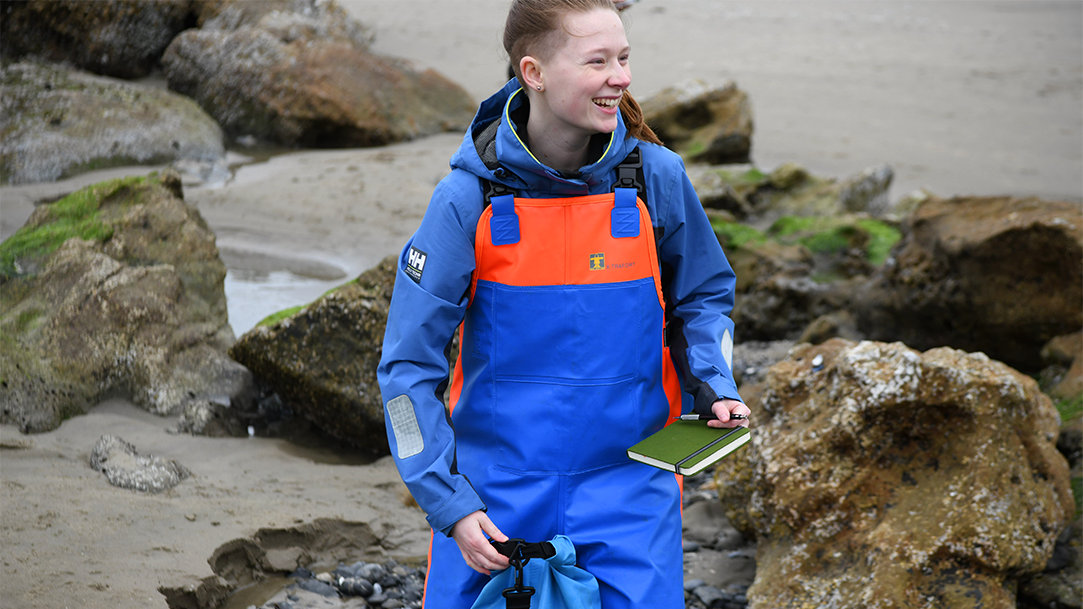 Person standing near tide pools along a rocky shoreline