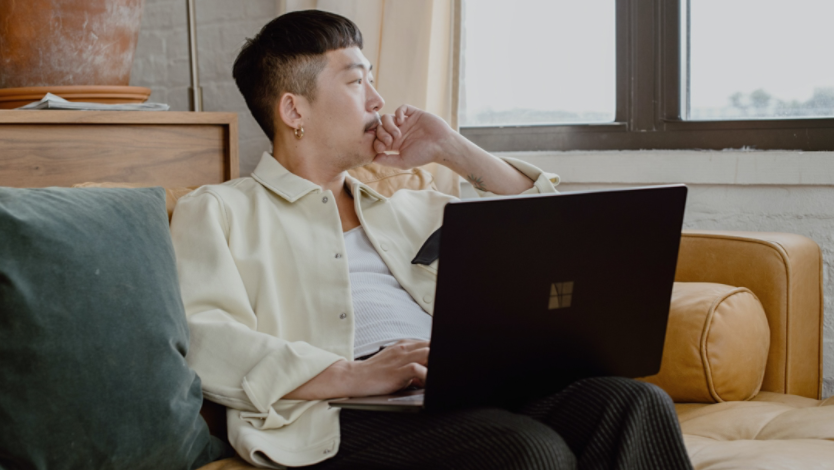 Person using a Surface laptop while looking out their window
