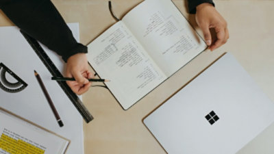 Person using a notebook next to a Surface laptop