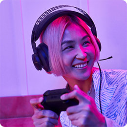 Una persona de cabello corto con audífonos puestos sostiene un control de juego.