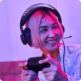 Person with short hair wearing headphones and holding a game controller