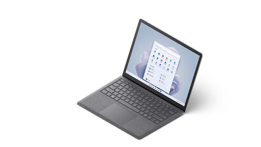 Windows 11 スタート画面を表示し、4 分の 3 ほど見えた状態のプラチナ カラーで Alcantara 素材の 13.5 インチ Surface Laptop 5:。