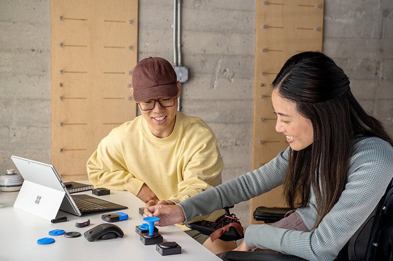 顧客が Microsoft アダプティブ アクセサリを使用して Surface Pro 9 デバイスを使用できるよう一緒に作業する作業療法士。