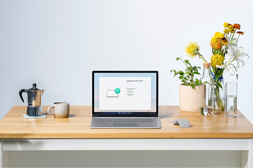 一台 Surface Laptop 4 放在桌面上，设备右边放着花