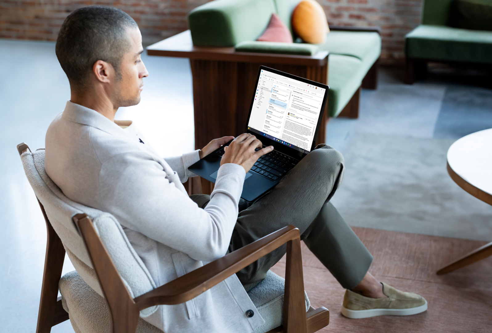 Een man zit op een stoel met Surface Laptop 6 op zijn schoot