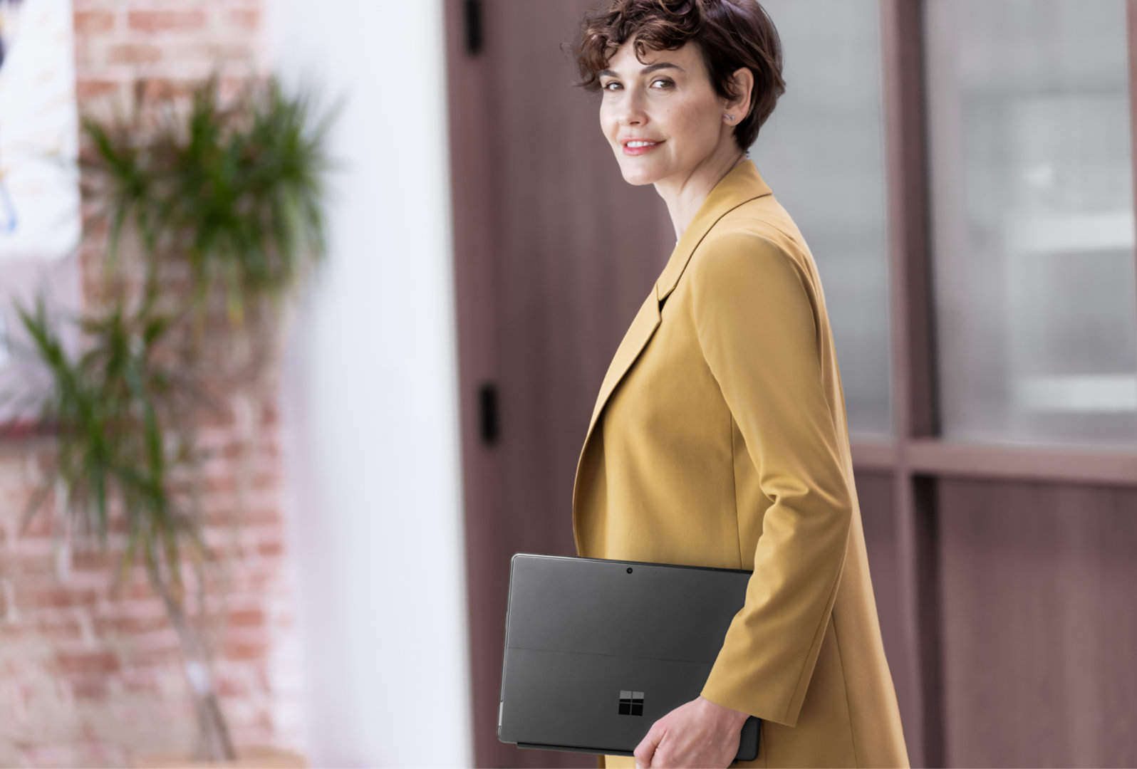 ผู้หญิงคนหนึ่งถือ Surface Pro 10 เดินเข้ามาในสำนักงาน